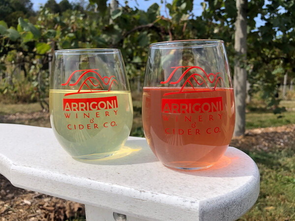 Two hard ciders side by side in a vineyard background.
